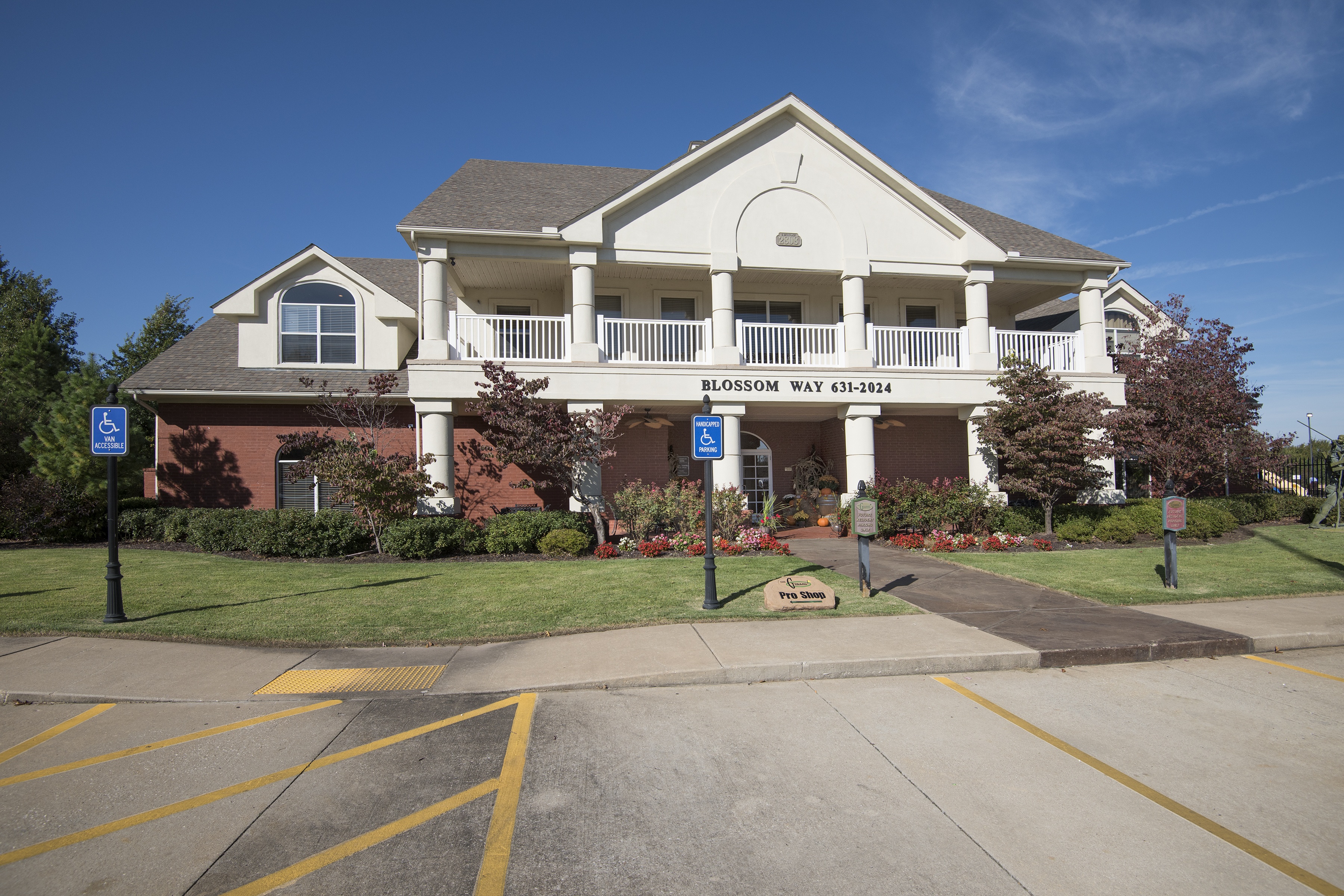 A large white building with a balcony and a sign that says Blossom Way.